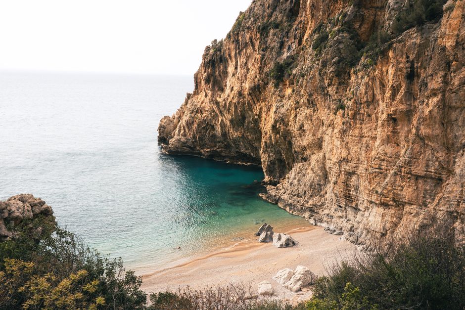 Breathtaking view of steep coastal cliffs and serene beach in Hatay, Türkiye.