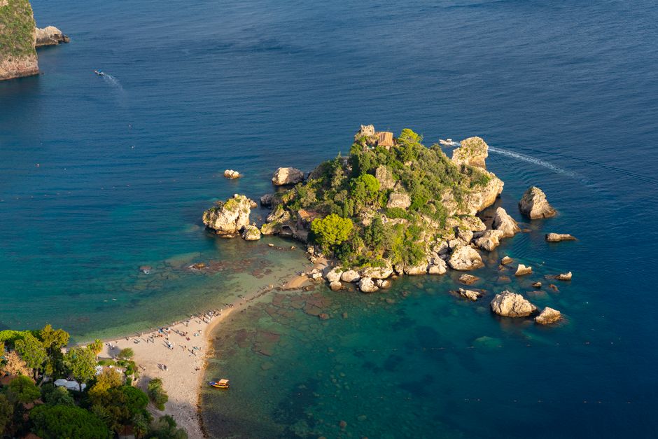 A breathtaking aerial shot of Isola Bella in Sicily, Italy, showcasing its vibrant greenery and crystal-clear 