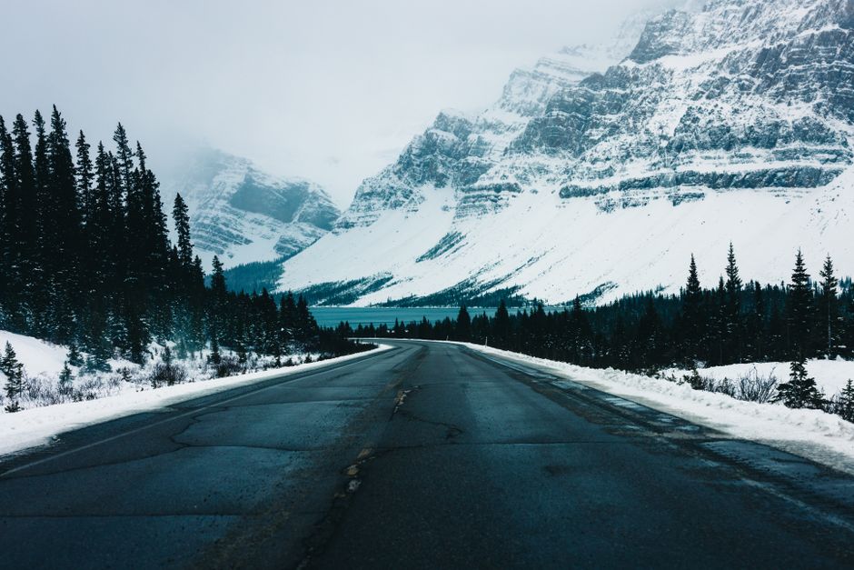 A breathtaking view of a snowy road through Jasper National Park with majestic mountains