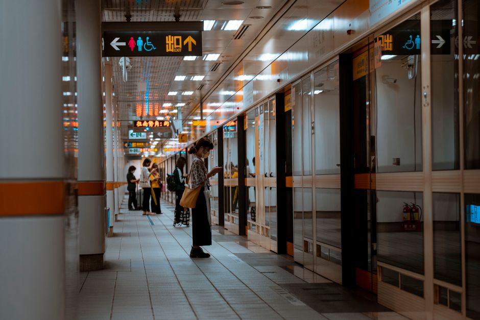 A bustling subway corridor with people standing and waiting near directional signs