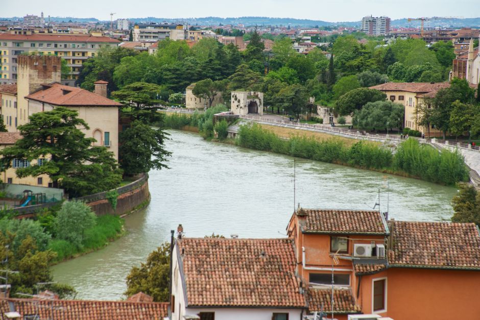 A picturesque view of Verona, Italy, featuring the Adige River and lush greenery