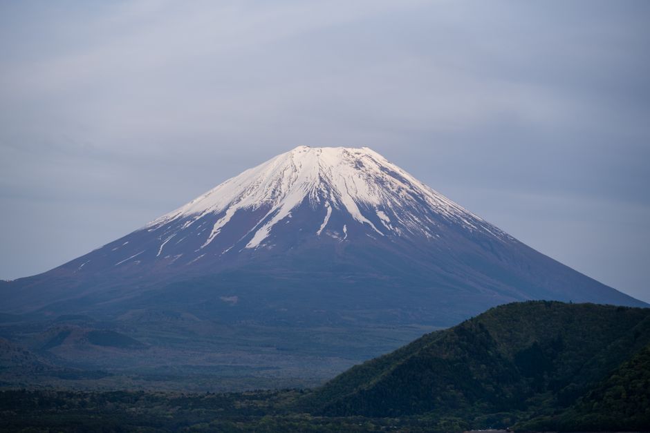 A stunning view of Mount Fuji with snow capped peak against a serene blue sky