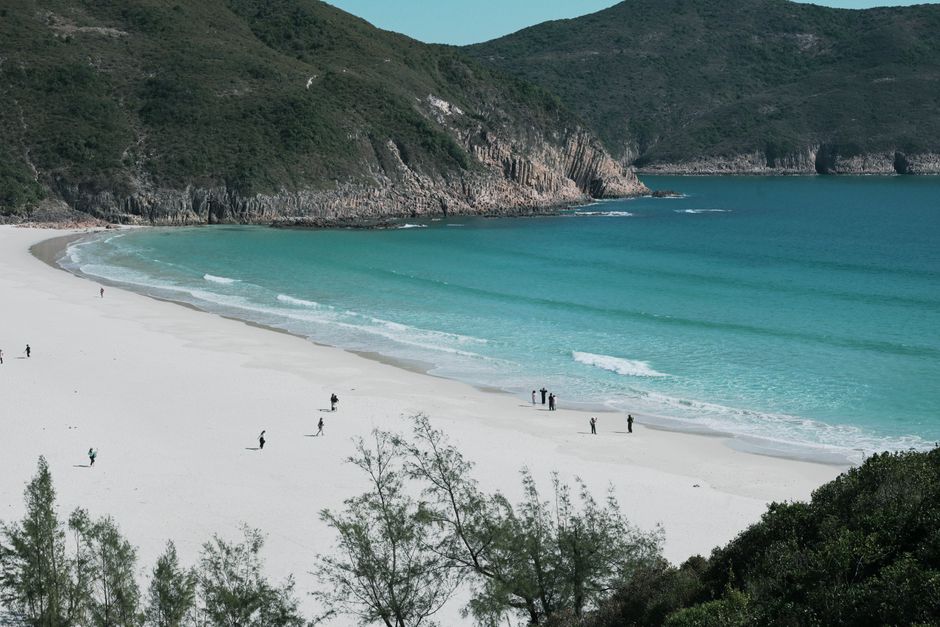 A tranquil beach scene with turquoise waters and people enjoying the sandy shore
