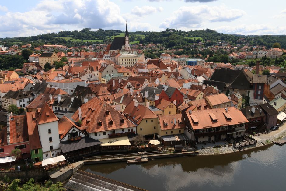 Aerial view of Český Krumlov showcasing picturesque red rooftops by the river under a cloudy sky