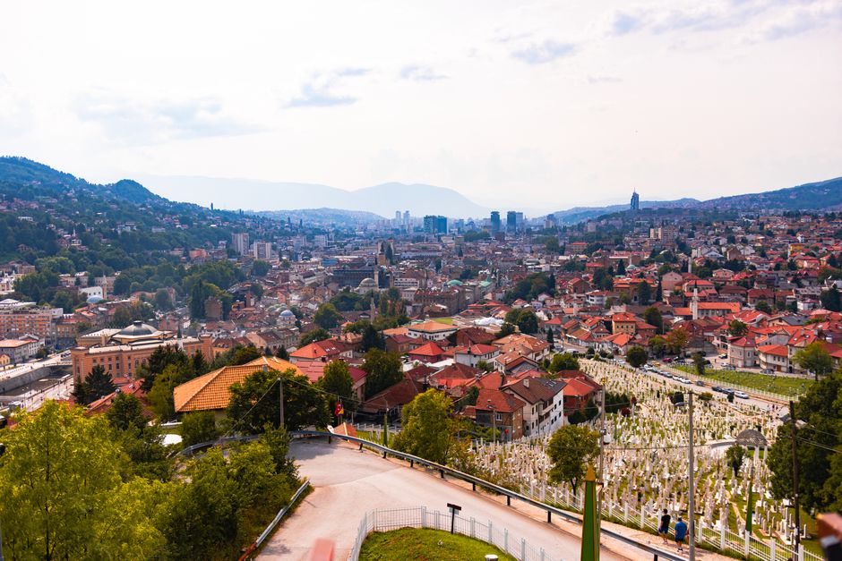 Aerial view of Sarajevo, showcasing cityscape, red rooftops, and distant mountains