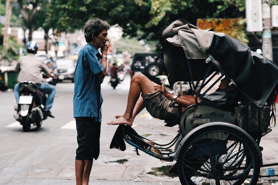 Candid street scene featuring a conversation between two men near a rickshaw in an urban setting.