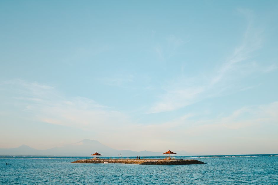 Tranquil island view with blue sky and calm ocean waters, perfect for relaxation imagery.