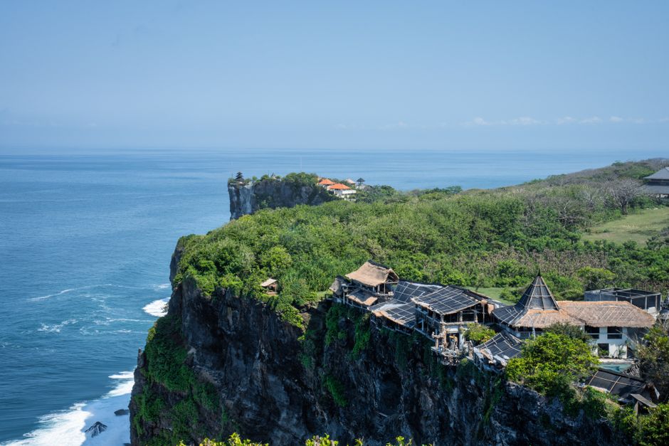 A breathtaking view of Uluwatu's cliffside with ocean and traditional huts, Bali.