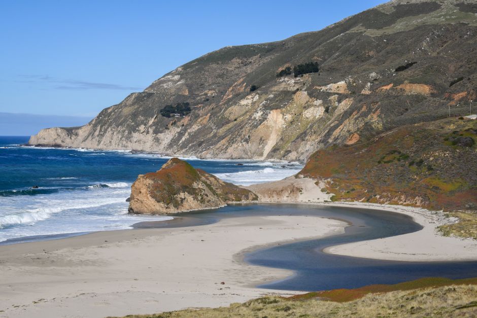 Beautiful coastal view of a blue ocean meeting sandy beaches with a winding estuary and dramatic cliffs