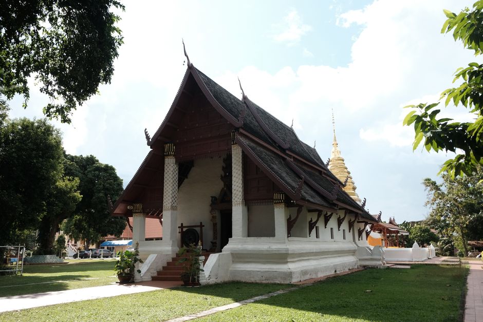 Beautiful Thai temple with traditional architecture amidst lush greenery on a sunny day