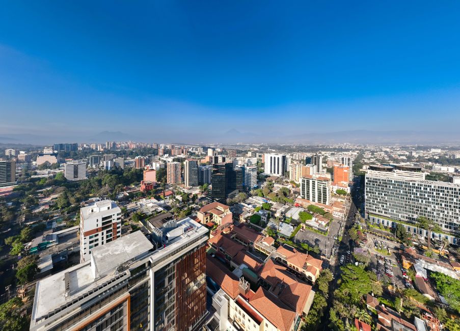 A breathtaking aerial view of an urban cityscape under a clear blue sky, showcasing modern architecture and vibrant city life.