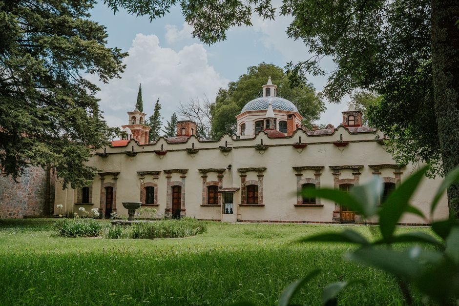 Colonial building with dome in a green, serene environment under a bright sky.