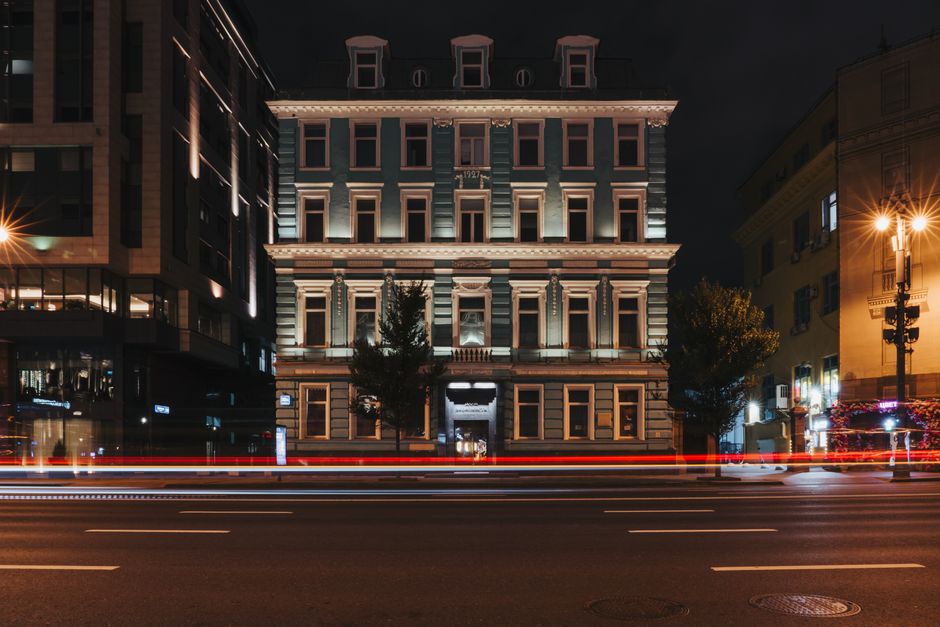 Elegant building facade at night with vibrant light trails on street.