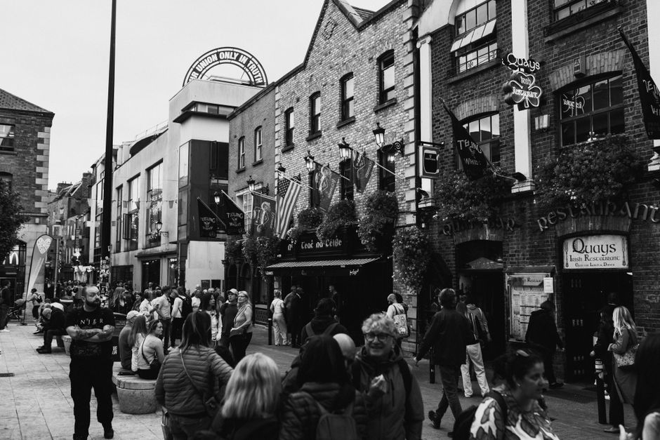 Black and white street scene capturing the vibrant atmosphere of Dublin's Temple Bar area. People are enjoying