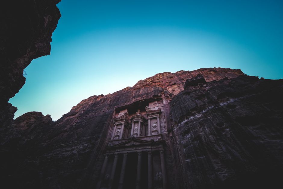 Breathtaking low-angle shot of Petra's ancient temple facade framed by rock canyons during sunrise