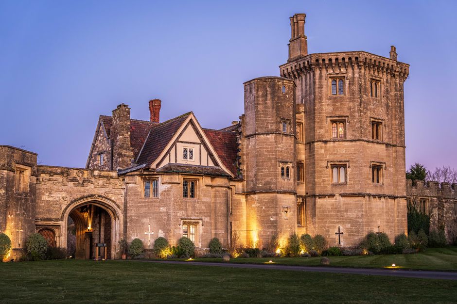 Charming historic castle with illuminated towers and stone walls at twilight, showcasing medieval architecture.