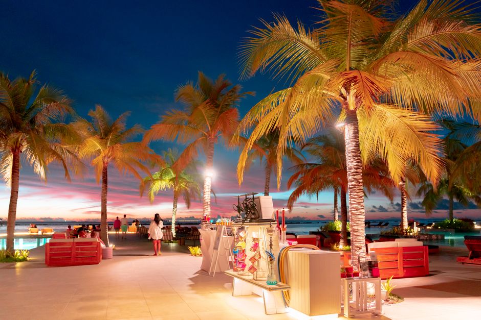 Relaxing tropical resort setting at sunset with palm trees and vibrant lighting.