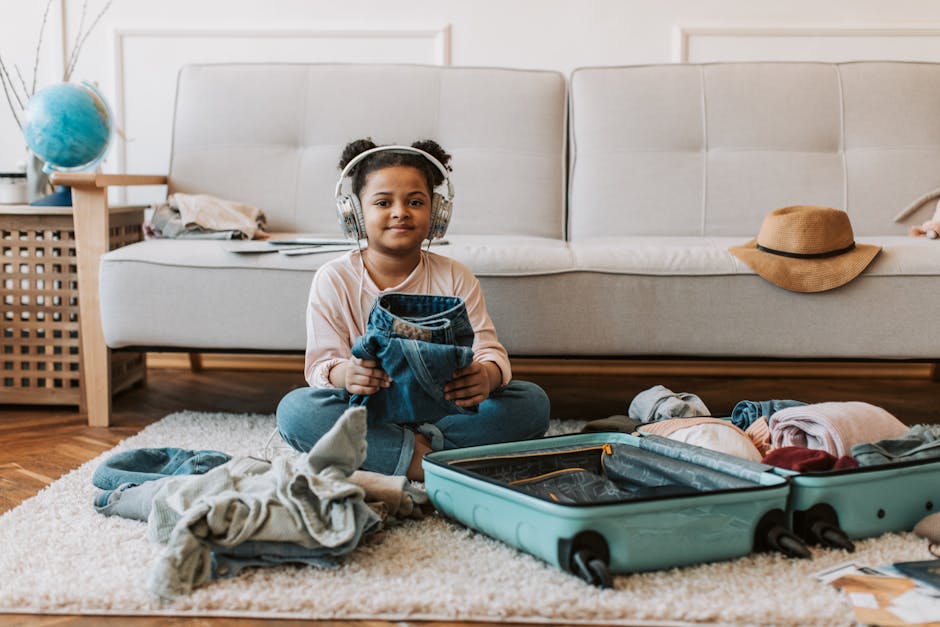 A child sitting on a carpet, packing clothes into a suitcase in a cozy living room.