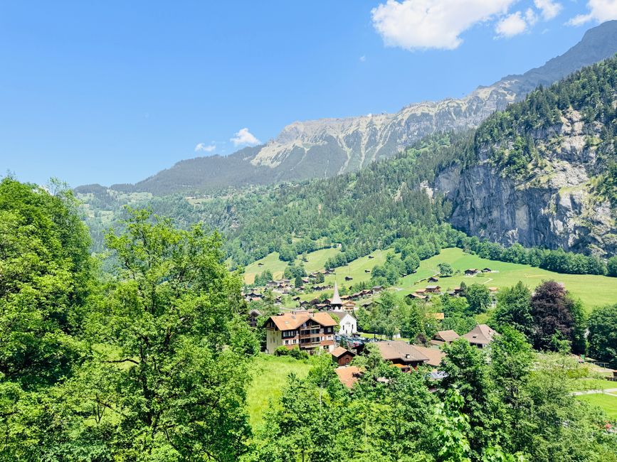 Charming Swiss village surrounded by lush green mountains and clear blue sky