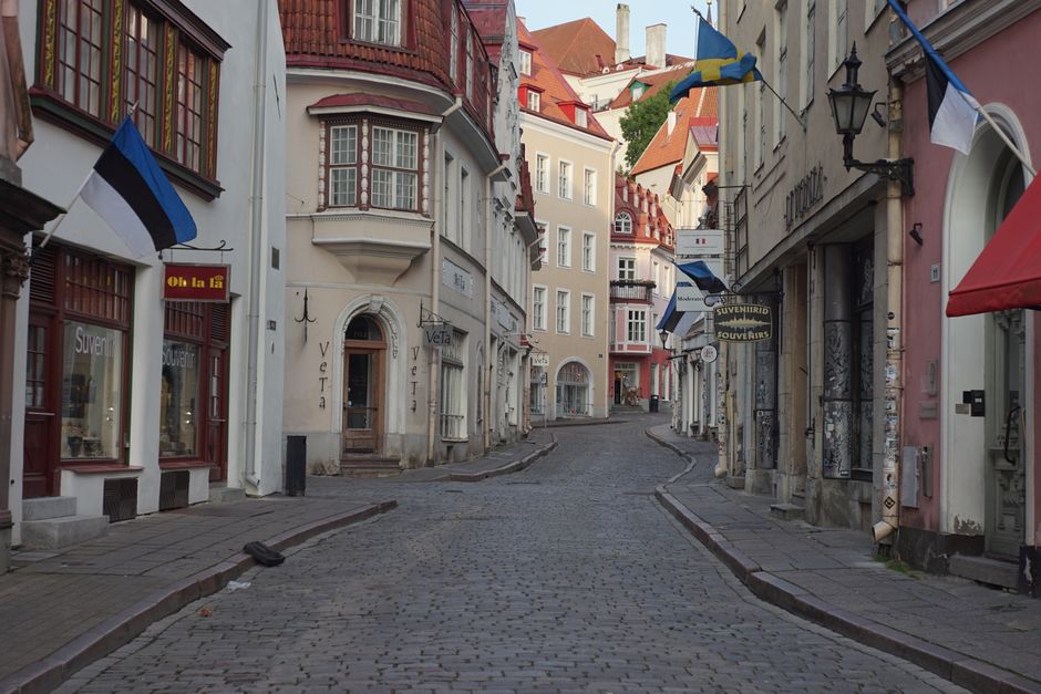 Cobbled street in the medieval heart of Tallinn, flanked by historic buildings and flags
