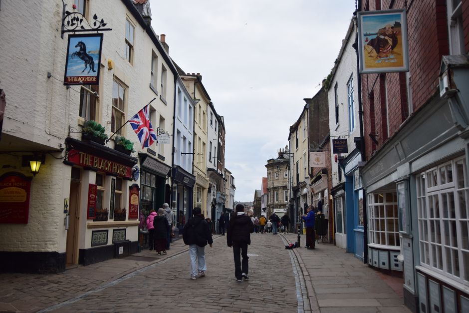 Cobblestone street lined with quaint shops and Union Jack flag in a historic English town
