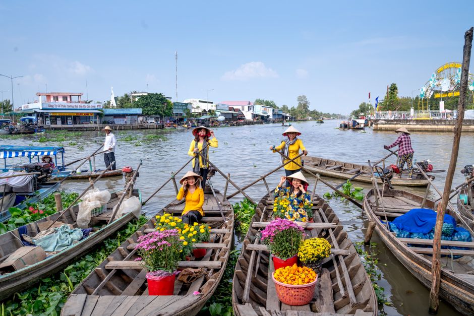 Colorful floating market in Vietnam featuring women on boats selling flowers and goods