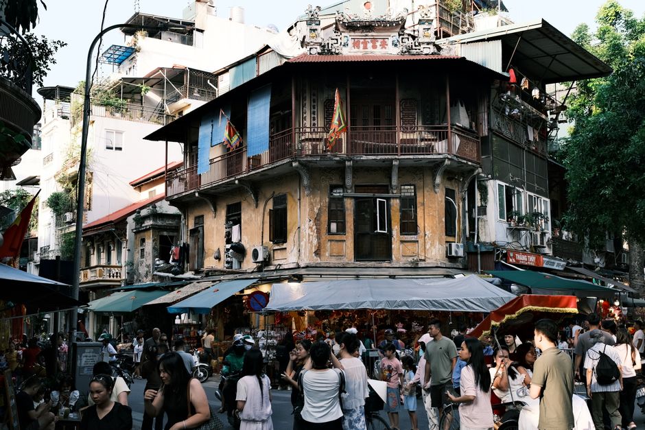 Crowded street scene in Hanoi with historic building and vibrant market activity