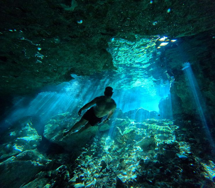 Diver explores a mesmerizing underwater cave with sunlight streaming through