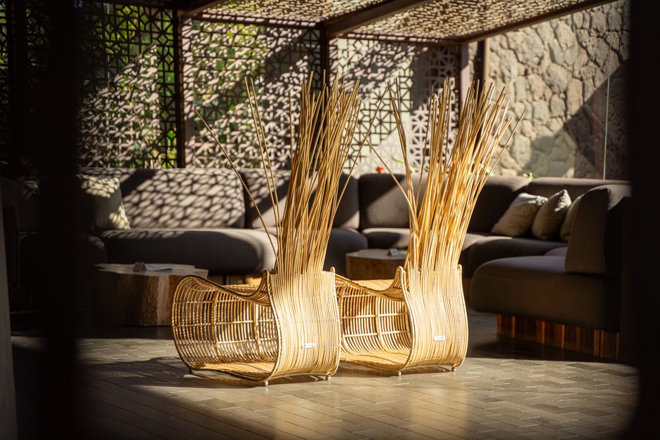 Modern rattan chairs in a stylish lounge with intricate metalwork design and soft lighting.