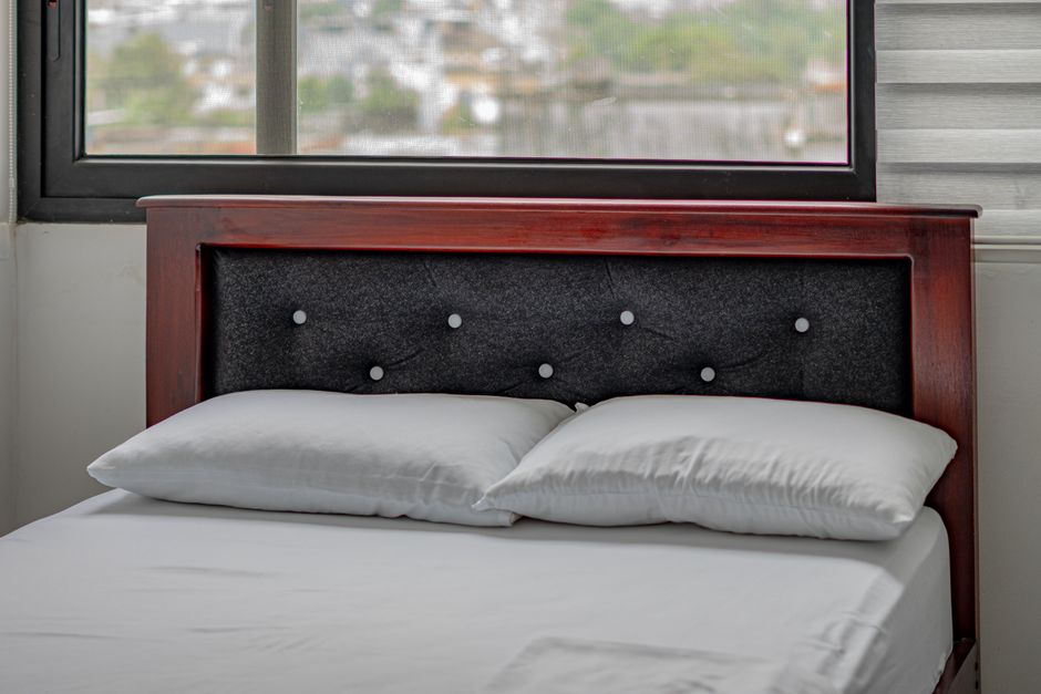 Modern bedroom with window view in Santo Domingo. Features a wooden headboard and comfortable bedding.