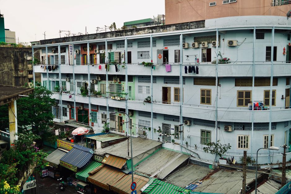 A street-level view of a multi-story apartment building with visible laundry and air conditioners.