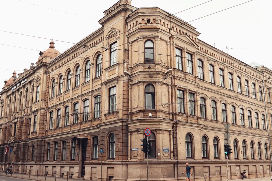 Elegant historic building facade in Riga's old town with a person walking by