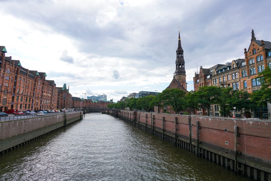Explore the picturesque canal in Hamburg with historic brick architecture under a cloudy sky