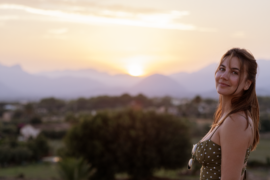 A woman enjoys a serene sunset in Palma, capturing the peaceful atmosphere.