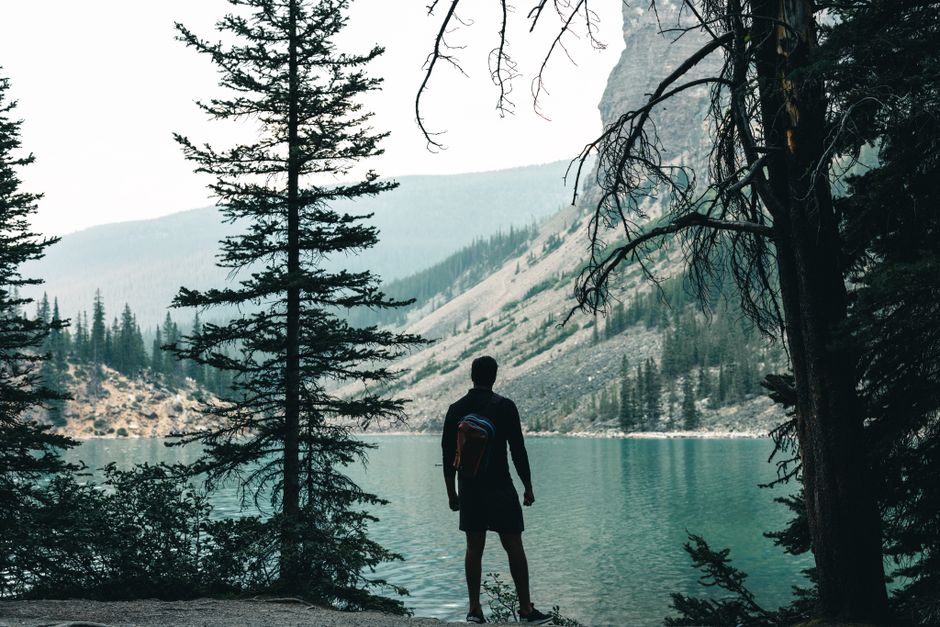 Silhouette of a hiker overlooking the turquoise waters of Moraine Lake in Banff, Canada.