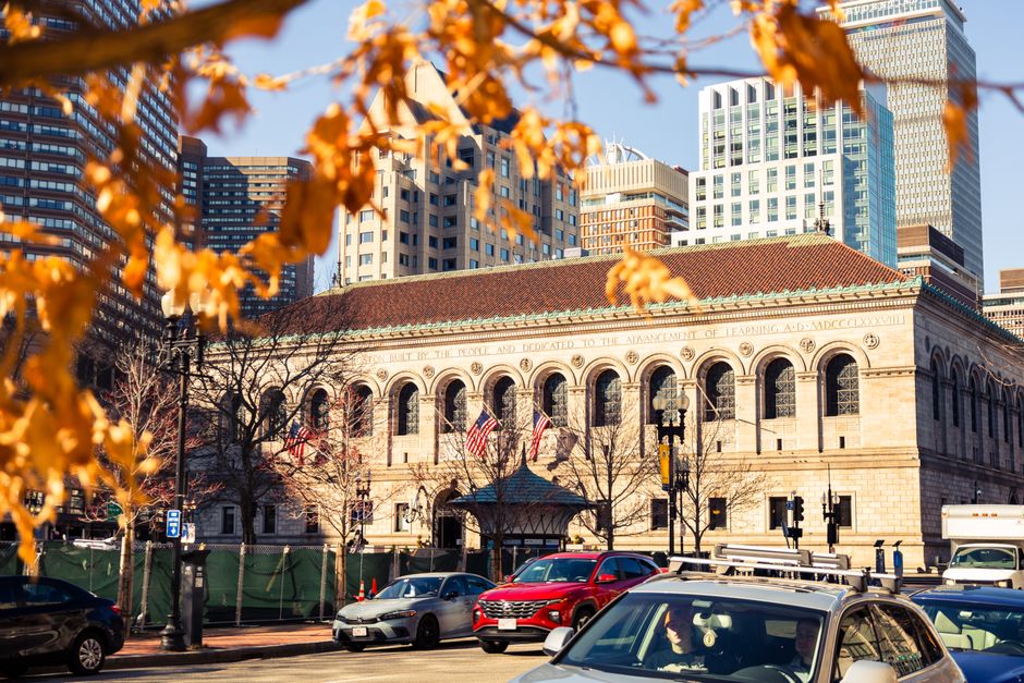 Historic Boston Public Library framed by autumn leaves in vibrant downtown cityscape