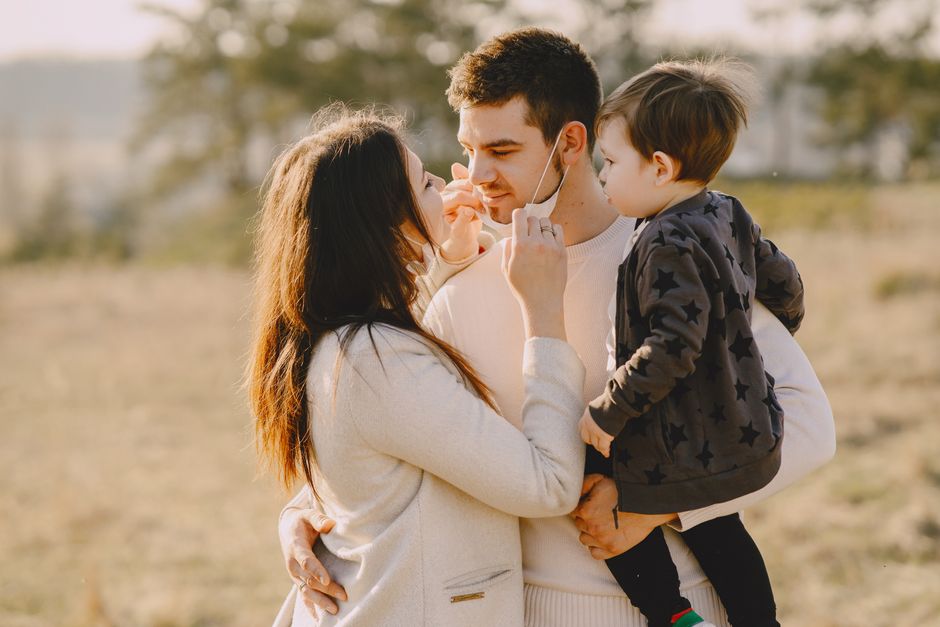 Family sharing affectionate moments outdoors with parents and child enjoying the sunny day.
