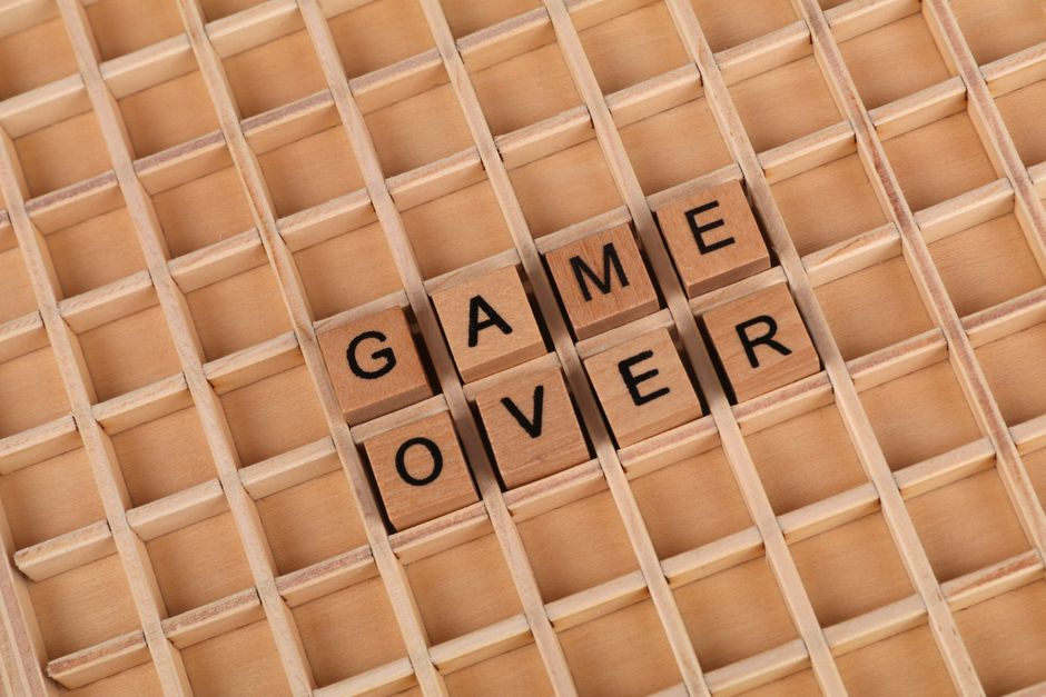 Close-up of wooden Scrabble tiles spelling 'Game Over' on a letter board.