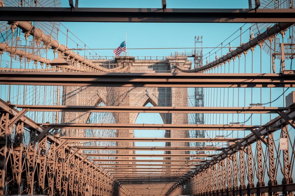 Iconic Brooklyn Bridge with American flag in clear daylight, showcasing its intricate architecture