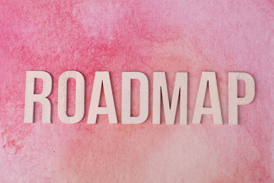 Wooden letters spelling 'ROADMAP' on a vibrant pink watercolor background.