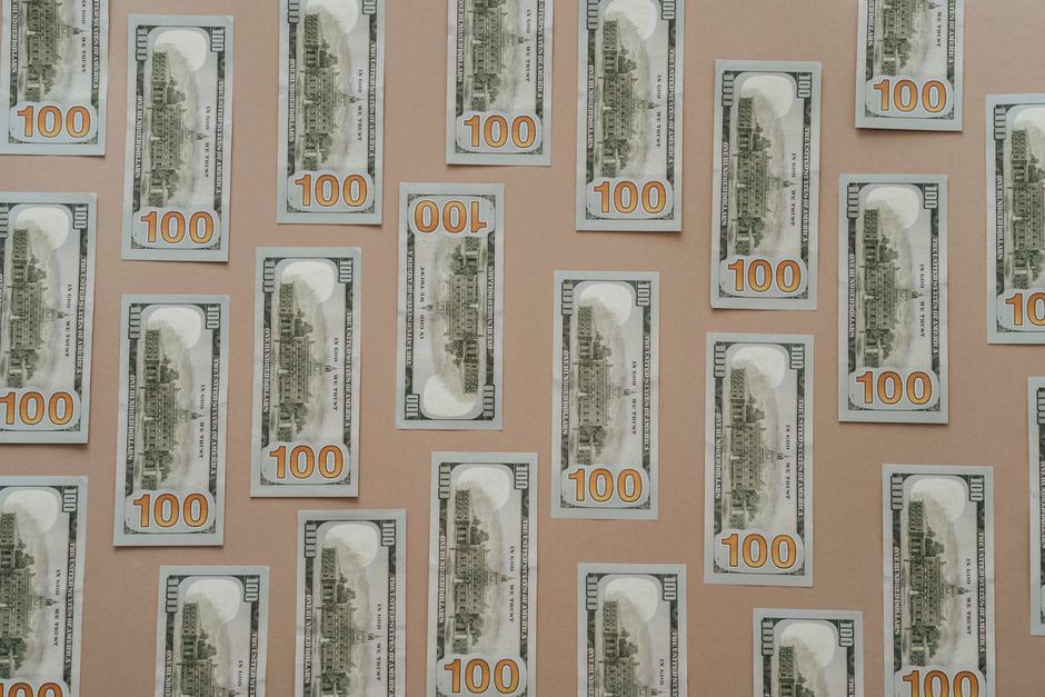 Flatlay of hundred dollar bills arranged on a surface representing wealth and finance.