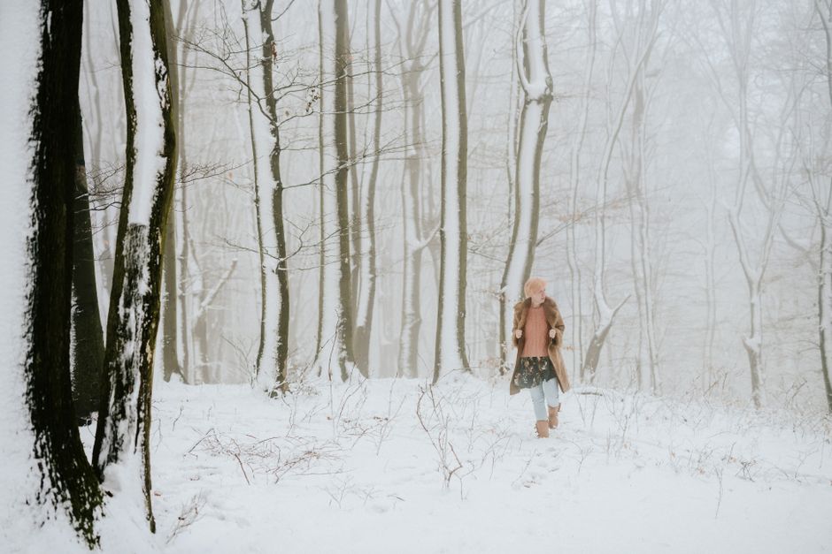 A woman walks through a snow-covered forest, capturing the serene beauty of winter.