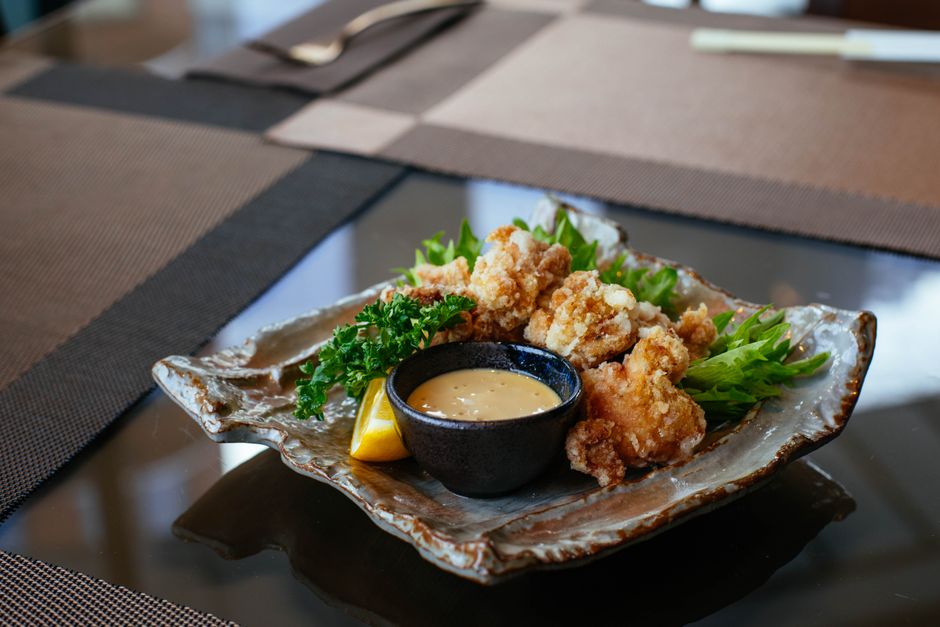 Delicious crispy fried chicken with dipping sauce served on elegant ceramic plate with garnish.