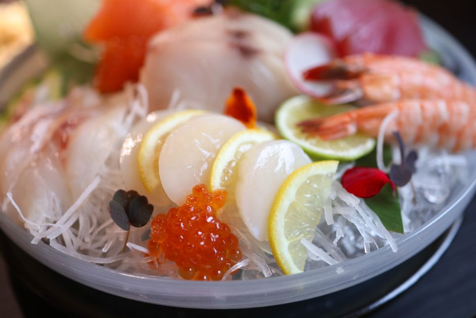 Close-up of a fresh sashimi platter featuring assorted seafood and vibrant garnishes.