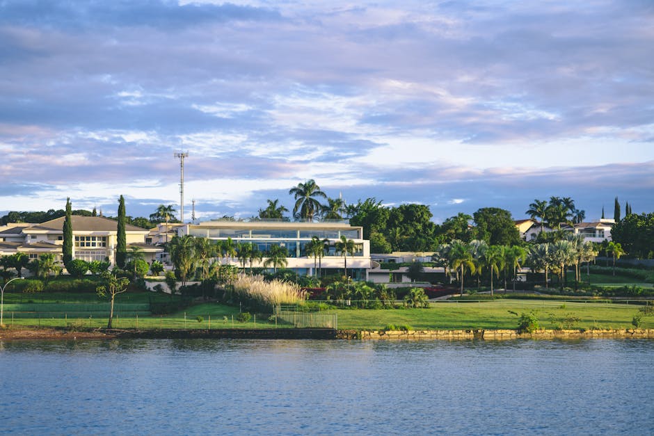 Elegant waterfront mansion surrounded by lush greenery and serene lake view.
