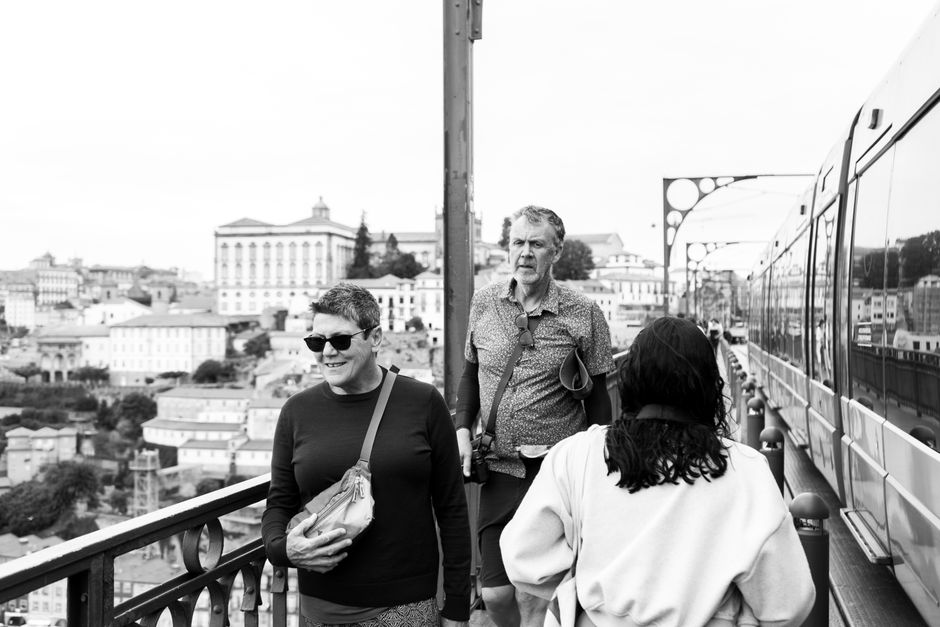 Black and white photo of pedestrians and tram crossing the iconic Dom Luís I Bridge in Porto, Portugal.