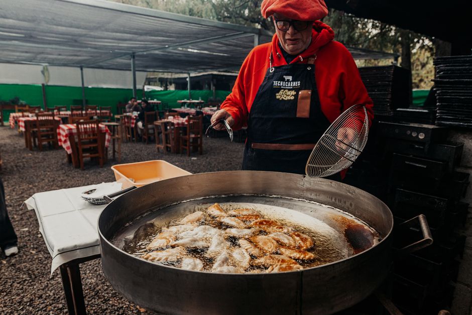 A chef frying empanadas outdoors in Provincia de Buenos Aires, showcasing Argentine cuisine.