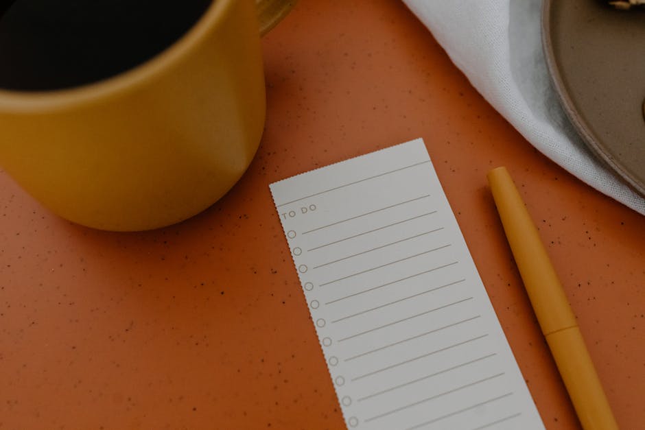 Flat lay of a mug, to-do list, and pen on an orange surface for planning inspiration.