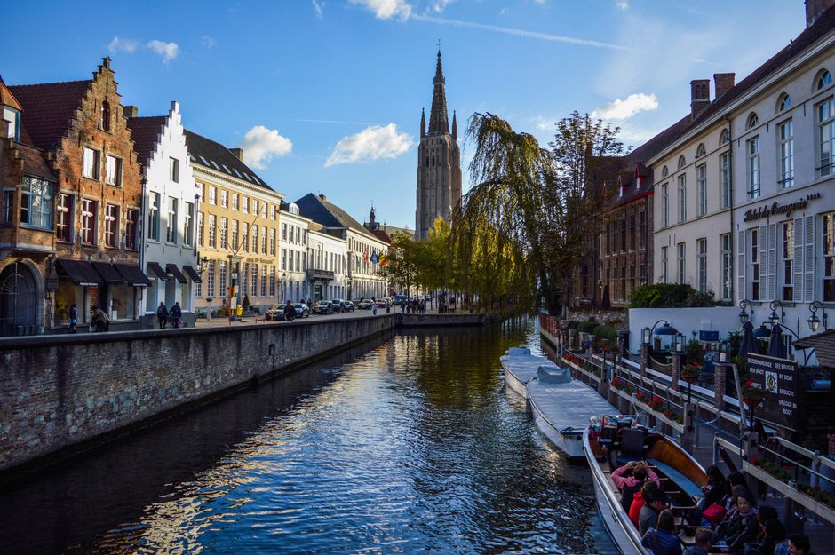 Picturesque scenery of rippling canal flowing near aged typical houses and historical Church of Our Lady again