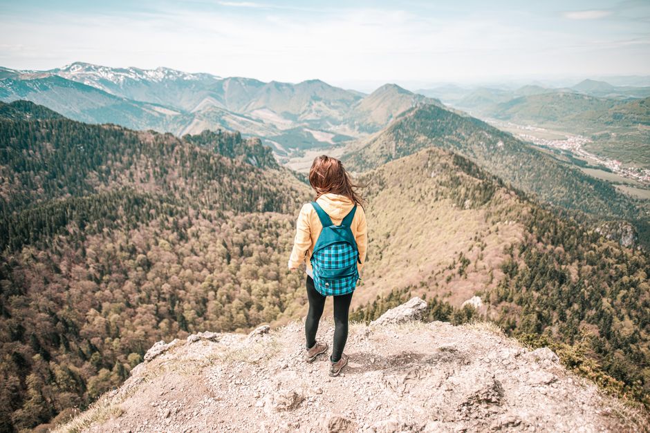 Woman overlooks Malá Fatra mountain range in Slovakia. Captivating scenic view from peak.